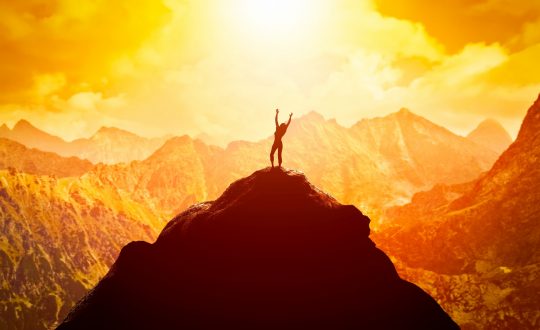 Happy woman on peak of the mountain enjoying the success, freedom and bright future.